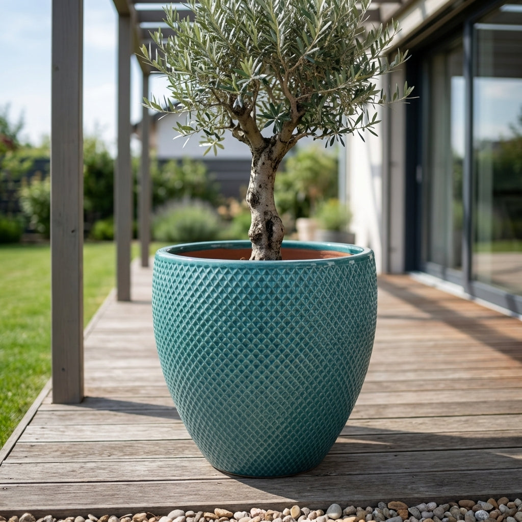 Detailní pohled na tyrkysový keramický květináč Signac s buxusem na slunné moderní rodinné terase.