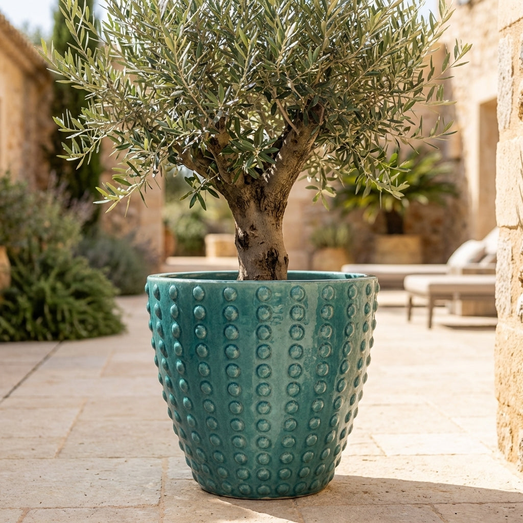 Detail na ručně vyráběný tyrkysový keramický květináč Attila z glazurované terakoty s reliéfní texturou na slunné středomořské terase.