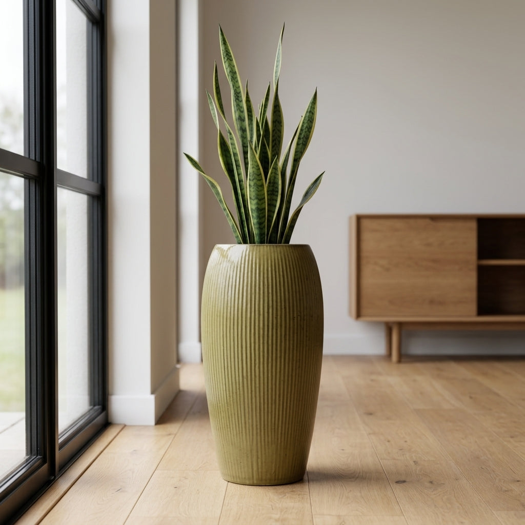 Žlutý keramický květináč Milano (61 cm) se strelícií v útulném skandinávském interiéru s dřevěnou podlahou. Detail ženy, která se jemně dotýká listu.