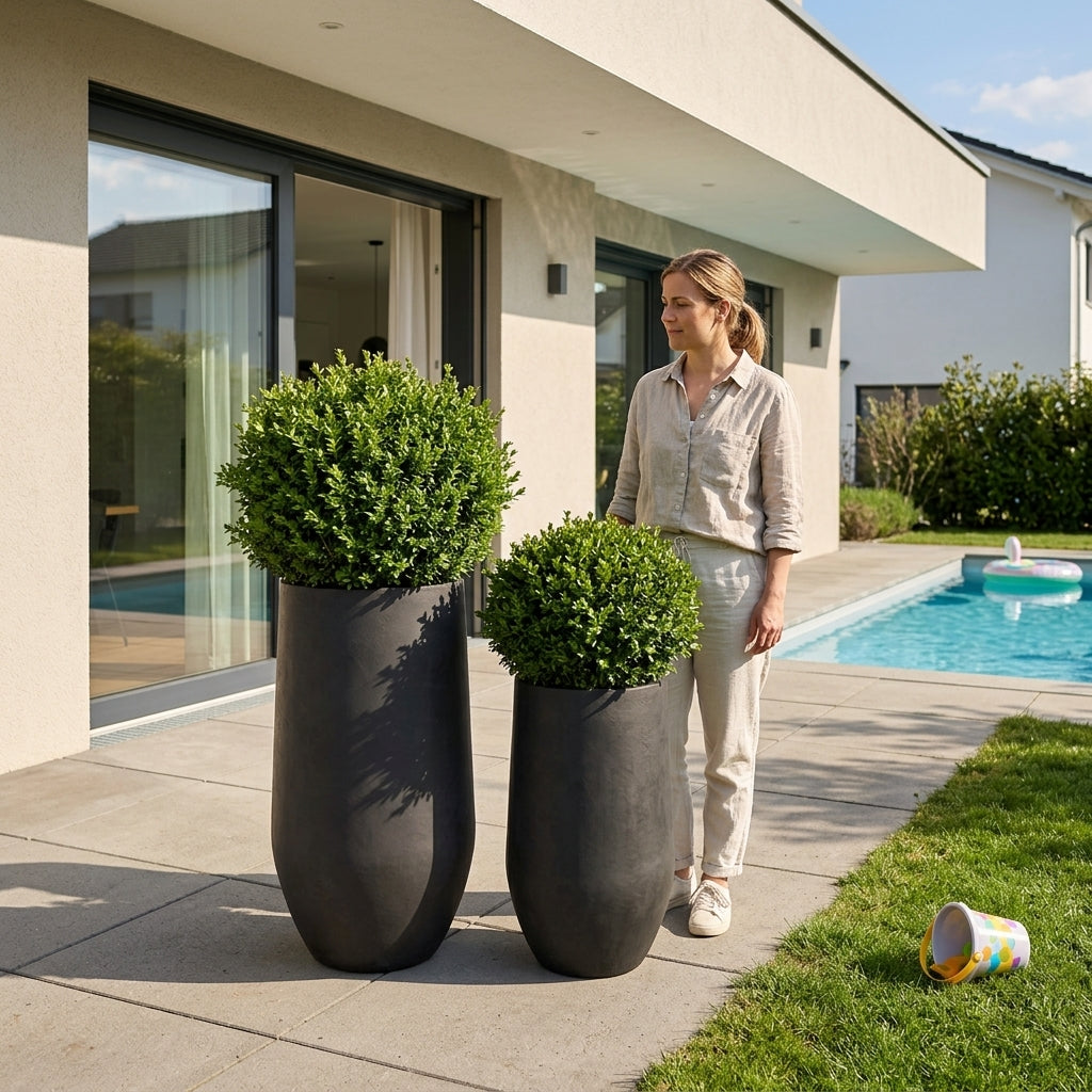 Hnědý betonový květináč Zenith XXL (40 x 80 cm) s keřem na moderní prosluněné terase u bazénu.