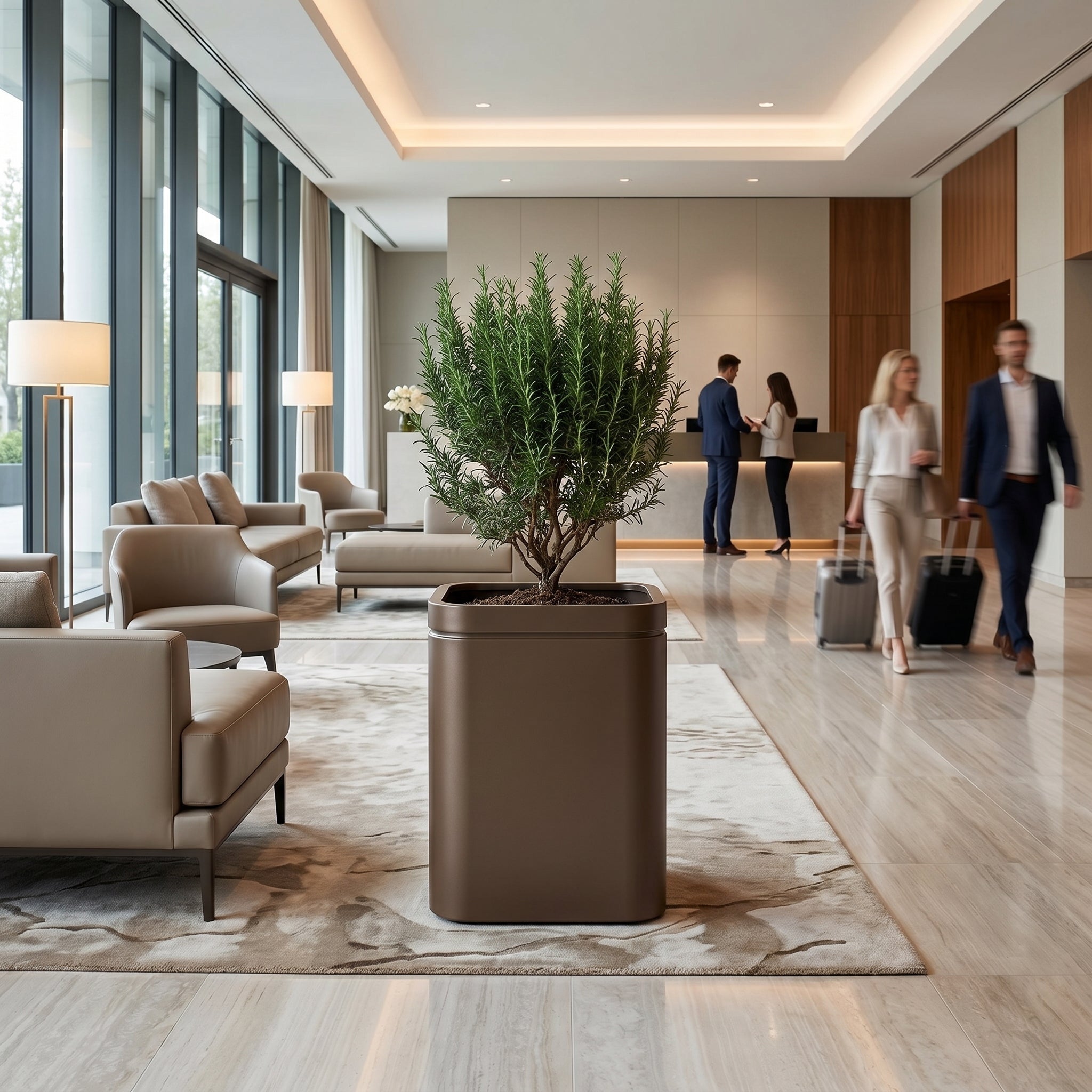 Velký pozinkovaný ocelový květináč INFINITY SQUARE v šedohnědé barvě (XL) s rozmarýnem jako dominanta moderního luxusního hotelového lobby s procházejícími hosty v pozadí.