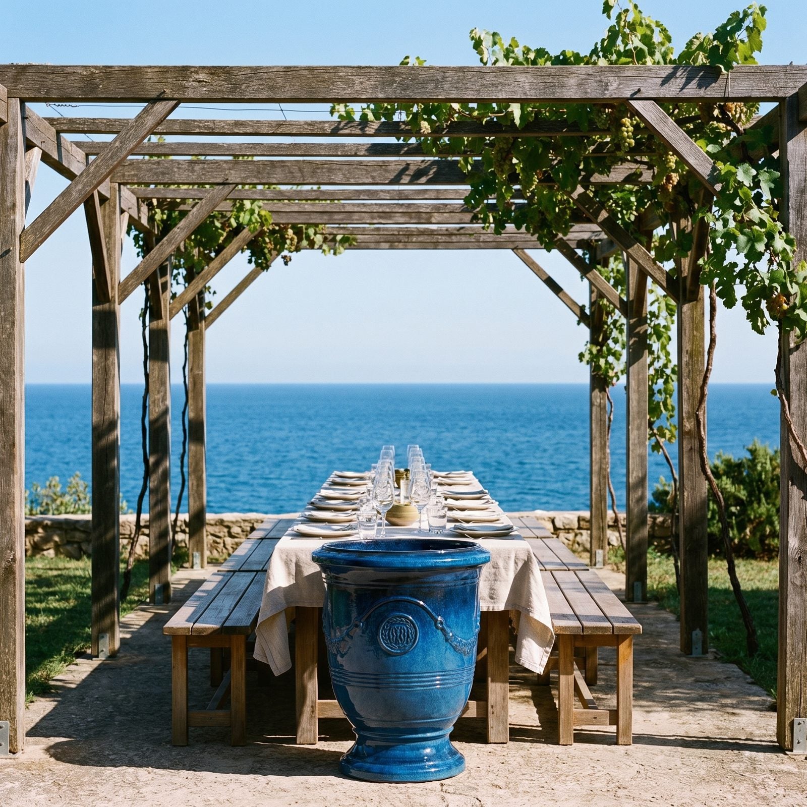 Gedeckter Tisch unter der Pergola mit Meerblick, flankiert von zwei RICHELIEU Azurblau