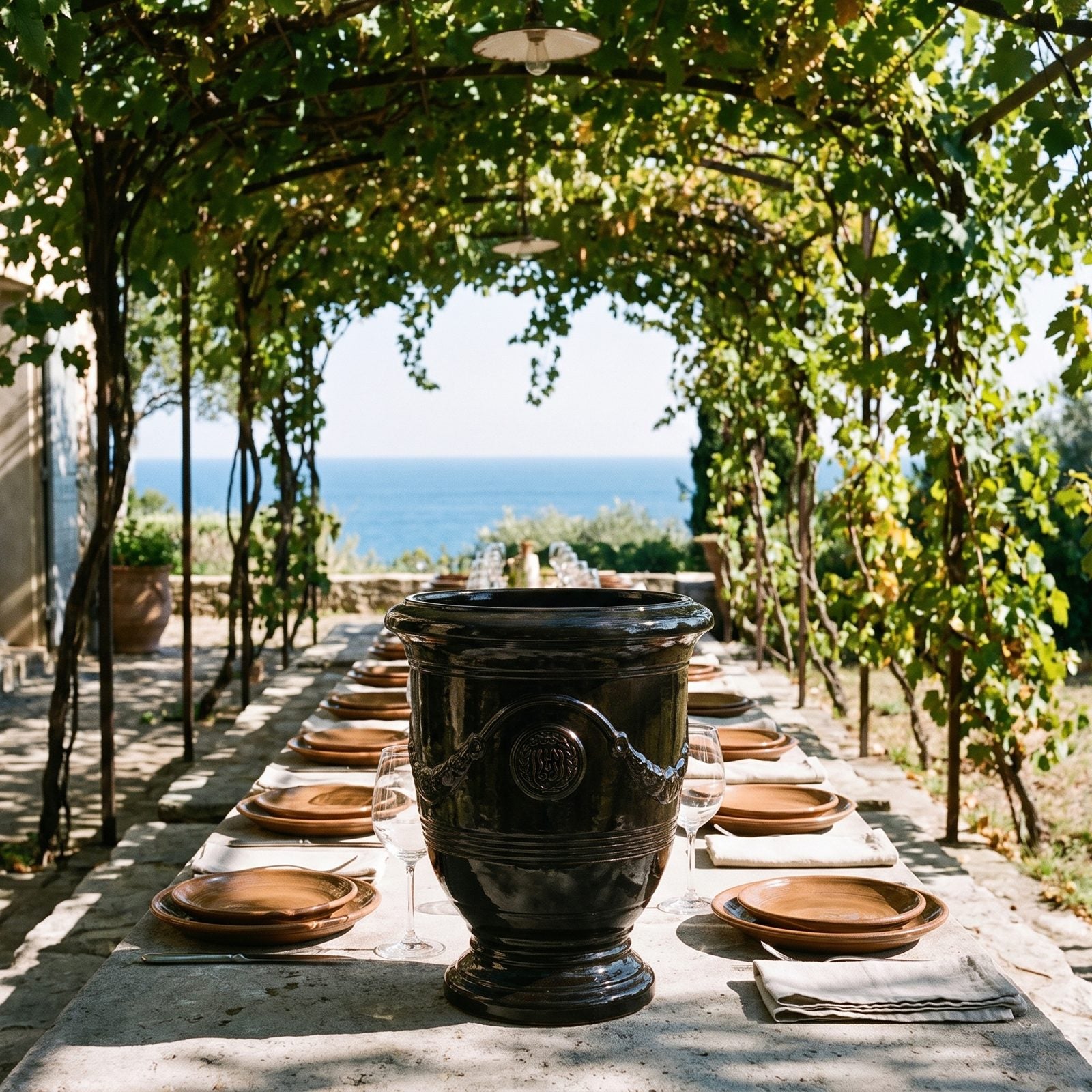 Gedeckter Tisch unter der Pergola mit Meerblick, flankiert von zwei RICHELIEU Schwarz