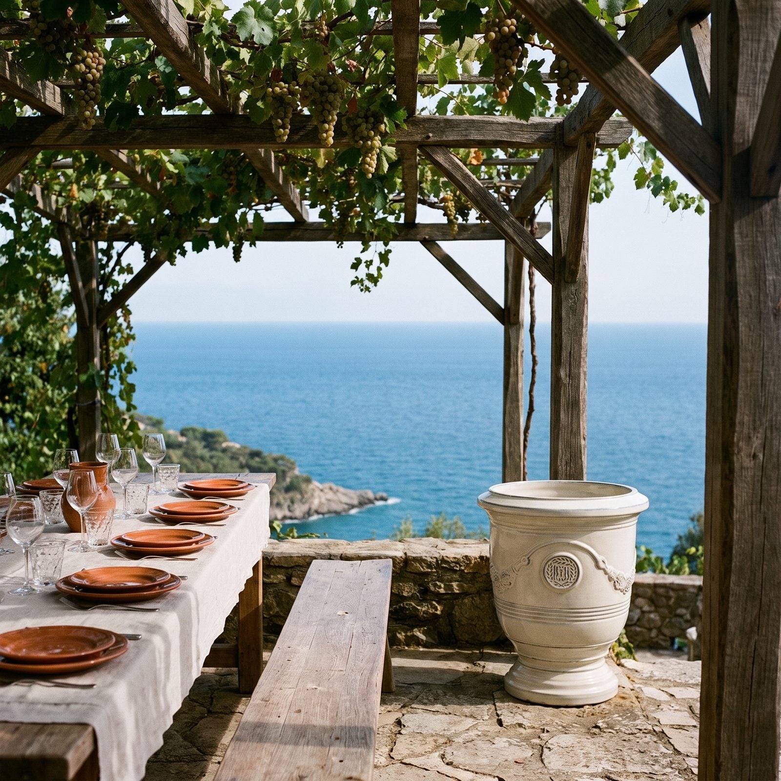 Gedeckter Tisch unter der Pergola mit Meerblick, flankiert von zwei RICHELIEU Creme