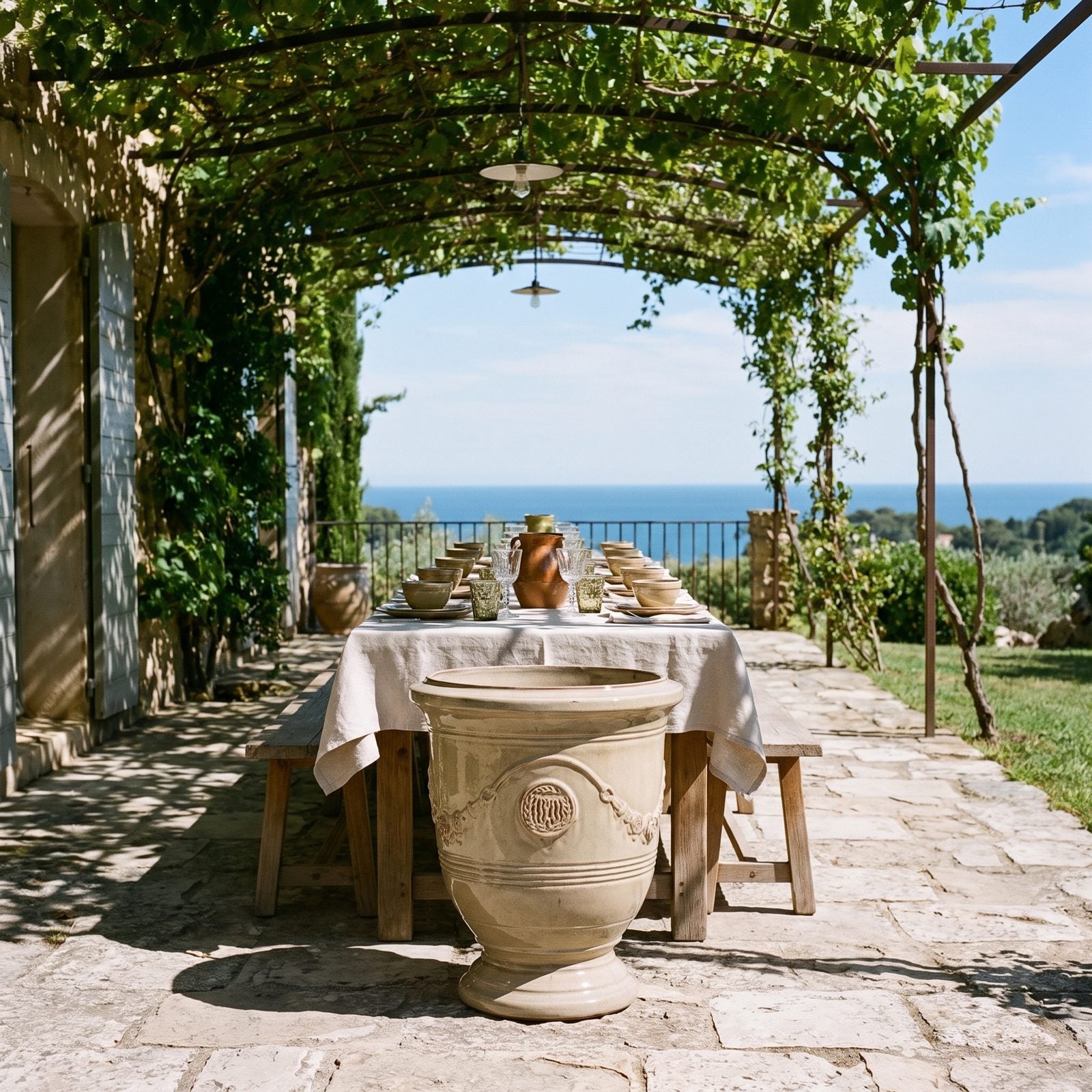Gedeckter Tisch unter der Pergola mit Meerblick, flankiert von zwei RICHELIEU Sandbronze