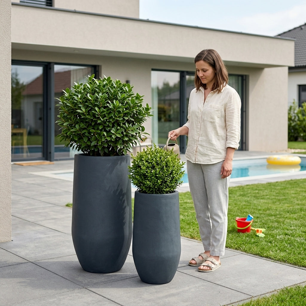 Betonový květináč Zenith - Tmavě šedý - XXL (40x80 cm) osázený keřem v detailním záběru na moderní rodinné terase u bazénu.