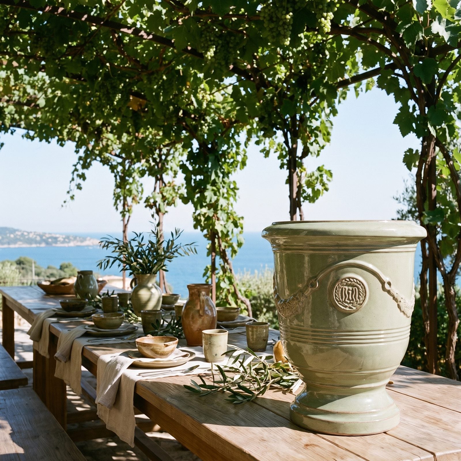 Gedeckter Tisch unter der Pergola mit Meerblick, flankiert von zwei RICHELIEU Jade-Perle